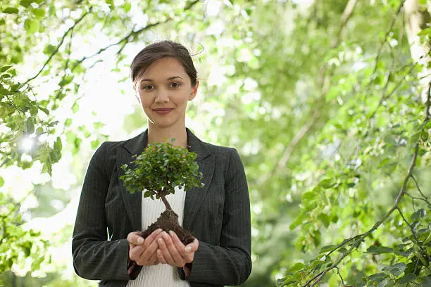 Photo of Businesswoman standing outdoors holding plant