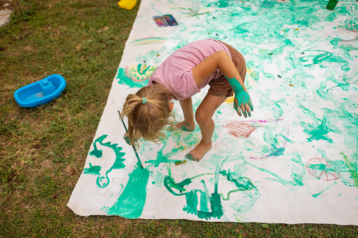 Children having a blast painting a big canvas in the backyard