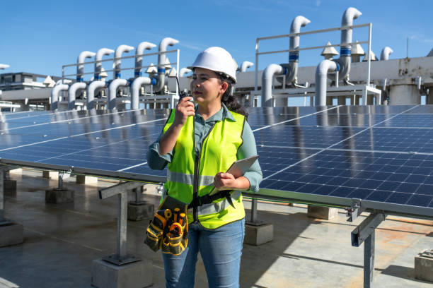 istock Happy female maintenance technician wearing protective workwear holding digital tablet and scientific instruments communicating with her team about solar cell panels performance, renewable resource and green technology 1698796925