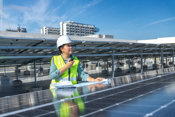 istock Happy solar energy engineer working outdoor in solar farm with communication device and blueprint documents, female solar engineer applying photovoltaic system as green technology and innovation 1698797492
