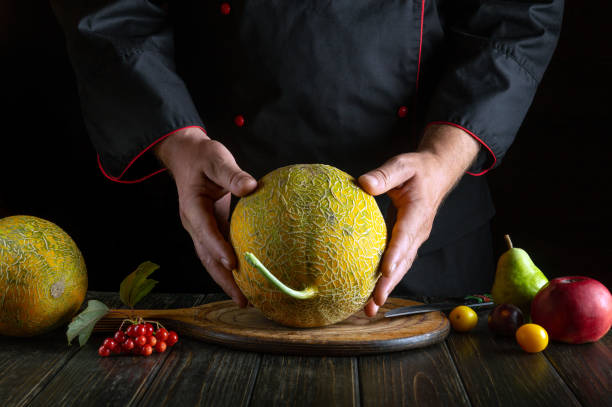 istock The chef holds a ripe melon in his hands before cooking in the kitchen. Fruit diet concept on dark background. Asian cuisine 1698831498