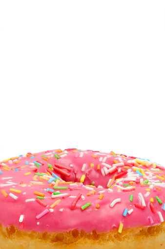 Donut with pink icing and multicolored sugar sprinkles.On white background,closeup