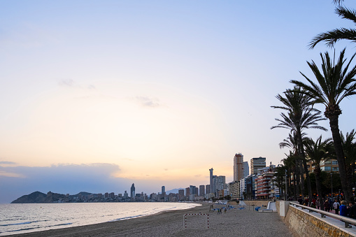 People strolling at sunset on the promenade overlooking the Poniente Beach in Benidorm, a very popular tourist destination on the Costa Blanca