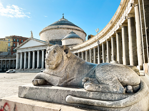 View at the Piazza del Plebiscito in Naples in Italy with the round cathedral at the background and the lion statues at the foreground