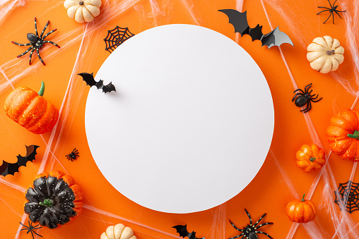 Get ready for a hair-raising Halloween night with orange isolated background adorned with creepy Halloween-themed decorations with empty round frame, perfect for advertising or text placement