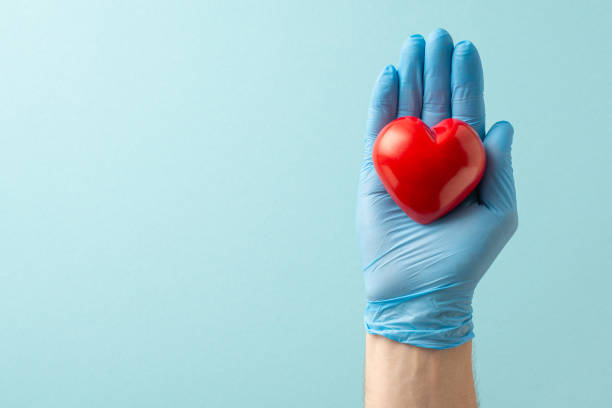 istock Highlight cardiovascular care with high angle view composition showcasing hands in medical gloves embracing heart on soft blue background with copy-space for text or advertorial purposes 1698846281