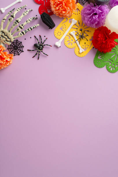 istock A festive tribute to Mexican heritage: vertical top-view image featuring skeleton's hand, vibrant flowers, confetti, and garlands. Spooky accents like cobweb, spider and small coffin enhance the scene 1698846353