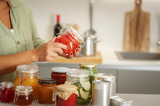 Close up of woman,s hands  holding a glass jar with preserved food