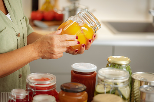 Preserving food. Close up of woman,s hands  holding a glass jar with preserved food. High resolution 42Mp indoors digital capture taken with Sony A7rII and Sony FE 90mm f2.8 macro G OSS lens