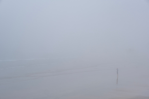A lone person on a cold and mist beach, Devon UK.