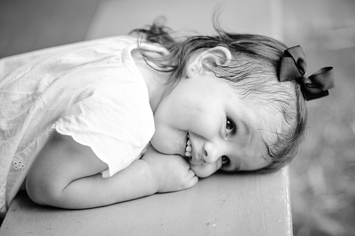 A close up portrait of an adorable 4 year old girl with a sweet smile. Black and white portrait on a white background.