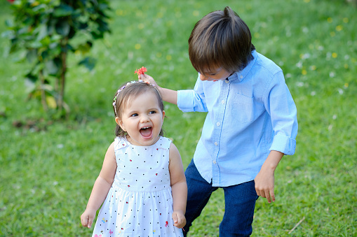 Boy and girl walking through a green meadow they look very happy and are smiling.