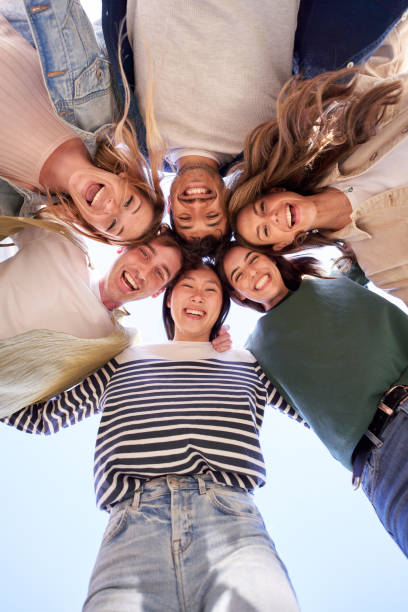 Vertical multiracial group young happy people standing in circle and smiling excited at camera.