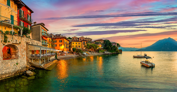The colorful houses of the old city of Menton, France shining at dawn, reflected in the Mediterranean water along Plage de Sablettes.