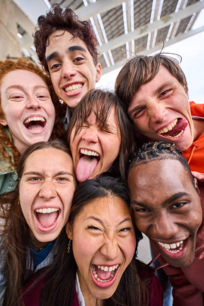 istock Vertical funny selfie of multiracial group young students together outdoors. Excited comic people. 1698958740