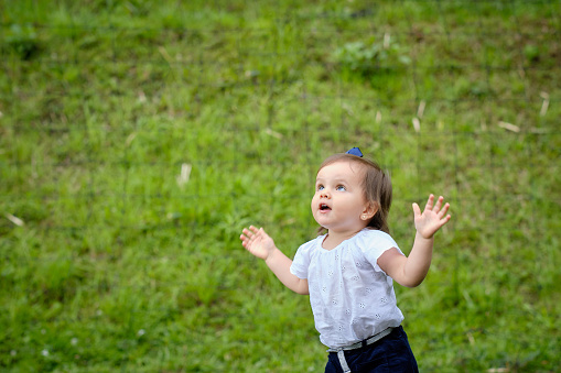 Cute three year old girl looking at the sky with open arms and very happy.