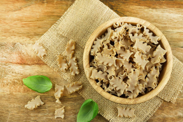 Italian wholemeal pasta, named Short Mafalda in a bowl isolated on wooden background. Italian food concept. Overhead view. Copy space.