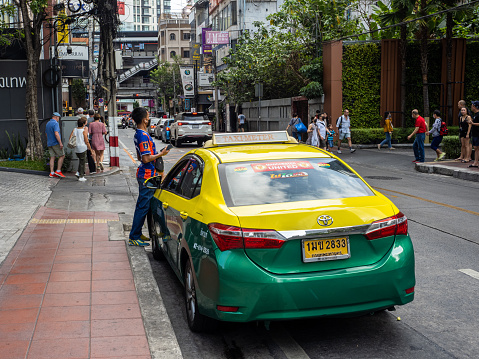 In the heart of Bangkok, a classic green and yellow taxi with its friendly driver patiently awaits passengers amidst the busy city streets. With its iconic green and yellow colors and traditional design, this taxi offers a glimpse of the city's rich culture and history while providing convenient transportation for locals and tourists alike.