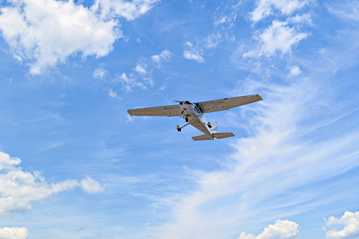 Single engine ultralight plane flying in the blue sky with white clouds