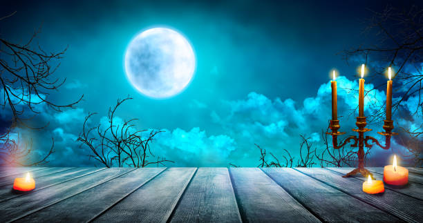 istock Smoke and mist on old wooden table with candles, defocused Halloween backdrop. 1699030147