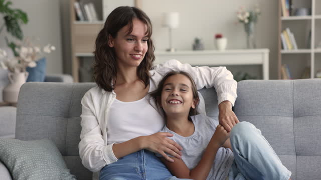 Happy young mom talking to positive preschool daughter with trust
