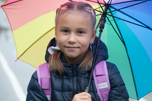 Happy little girl with umbrella. Small girl with umbrella in rainy weather. Happy childhood. School time. Autumn fashion. Child. Feeling protected at this autumn day.