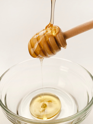 Honey dripping from honey dipper on a bowl. Fresh organic honey