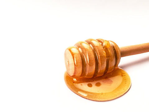 Honey and honey dipper on the white background with copy space