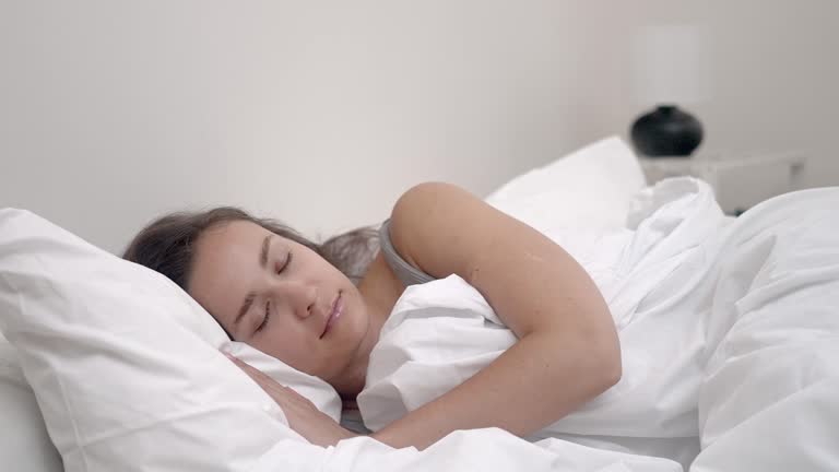 young woman peaceful sleep in bedroom, soft white blanket and a comfortable orthopedic mattress.