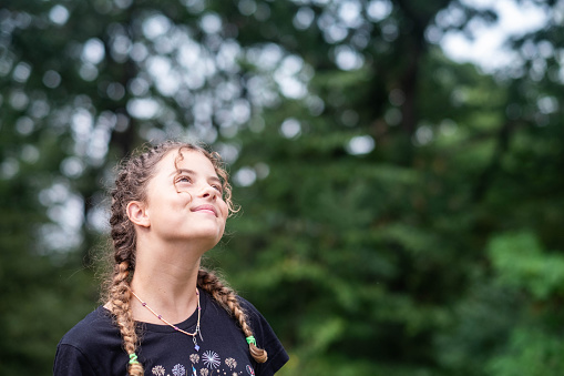happy curly girl with braids in nature looking at the sky