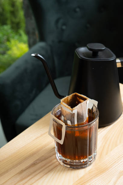 istock Glass cup with making coffee from drip bag on wooden table. Trends in making coffee at home. 1699084480