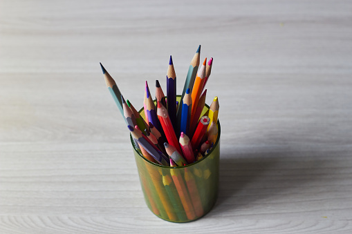 Photo colorful wooden pencils in a plastic cup on the table. Teaching children. Painting. Graphics.