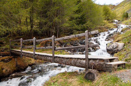 Close up of wooden bridge over a small river, part of a mountain trail in the forest. Lugo province, Galicia, Spain.