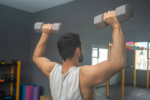 거울 앞에서 어깨 프레스를 하는 젊은 운동선수. - body building determination deltoid wellbeing 뉴스 사진 이미지