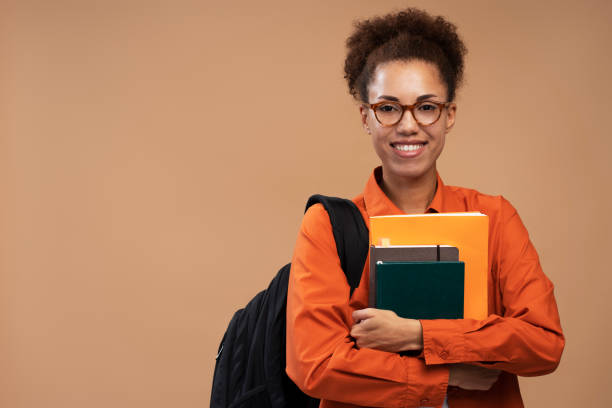 istock African American university student holding books and backpack isolated on background. Education 1699143696