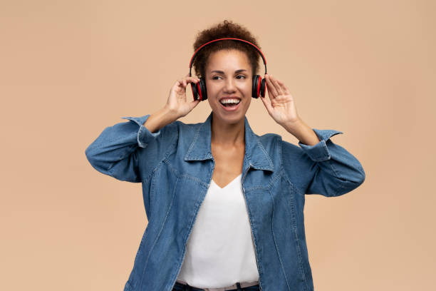 emocjonalna afroamerykanka słuchająca muzyki w słuchawkach bezprzewodowych w tle - neutral look audio zdjęcia i obrazy z banku zdjęć
