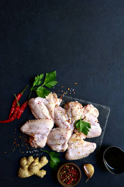 istock Raw chicken wings with ingredients for making. Top view with copy space. 1699156931