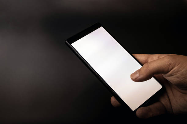 istock A hand holding a smartphone with a blank white screen on gray black dark background 1699177379
