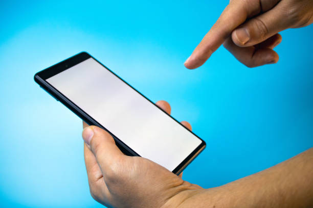 istock Hand holding smartphone with blank screen on blue background, click gesture 1699177951