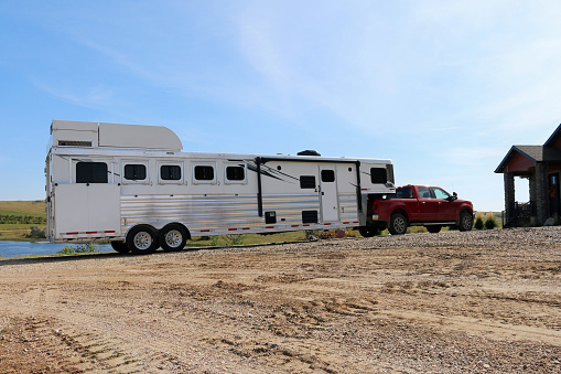 Large 5-horse slant reverse load camper living quarters gooseneck horse trailer hooked up to 1 ton towing pickup before a horse event.