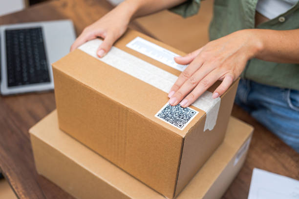 istock Online shopping close-up woman hands adding QR code sticker to package, e-commerce and delivery. 1699228043