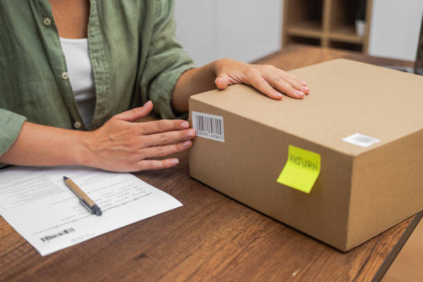 istock female shopper attaches barcode to cardboard box for online shopping refund, 1699228797