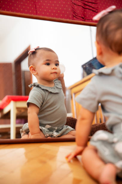 istock Cute baby girl looking at her reflection in the mirror 1699248580