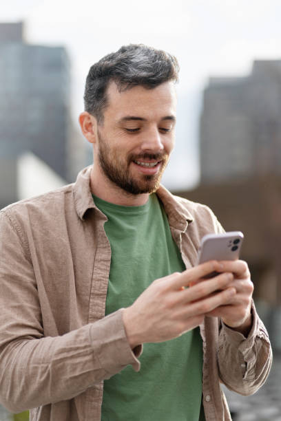 istock Handsome latin man holding mobile phone reading text message standing on the street 1699272030