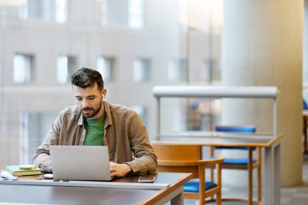 istock Middle aged man in wireless earphones sitting at desk, using laptop, workplace. Studying online 1699272032