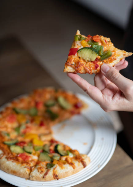 woman holds a piece of pizza hand and tastes it - gourmet enjoyment food freshness imagens e fotografias de stock