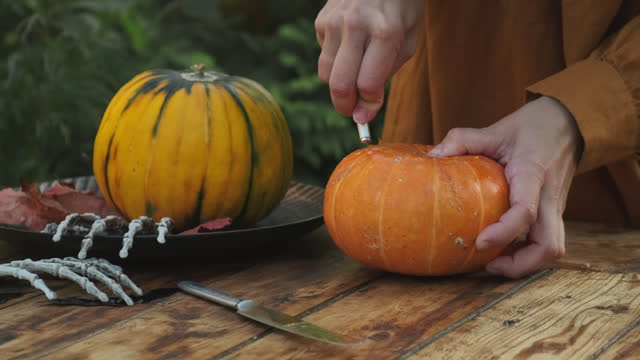DIY Halloween pumpkin. Woman hands carve jack o lantern from pumpkin.