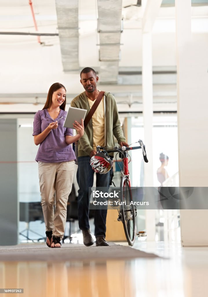 He's alway ready to help out a colleague Handsome young ethnic businessman ready to leave the office with his bicycle helping a colleague Bicycle Stock Photo