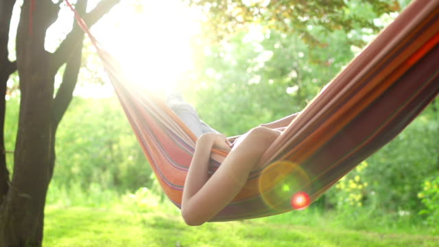 Young woman relaxing in a hammock under the trees