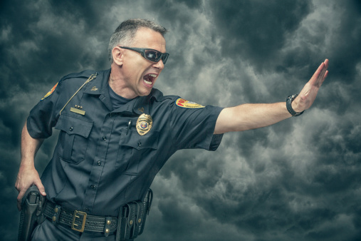 Policeman yelling and gesturing to stop. Arm Badge Create by me, Gold Chest Emblem Custom Ordered Generic. This stock image has a horizontal composition on a cloudy background.